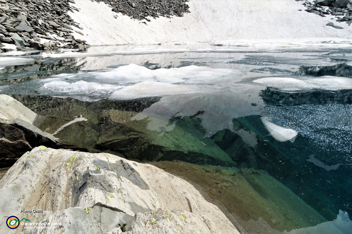 61 Le pareti rocciose si immergono nelle gelide acque del Lago del Vallone in disgelo.JPG